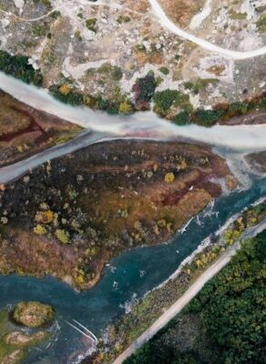 Vue aérienne de deux cours d’eau se rejoignant parmi bois et graviers
