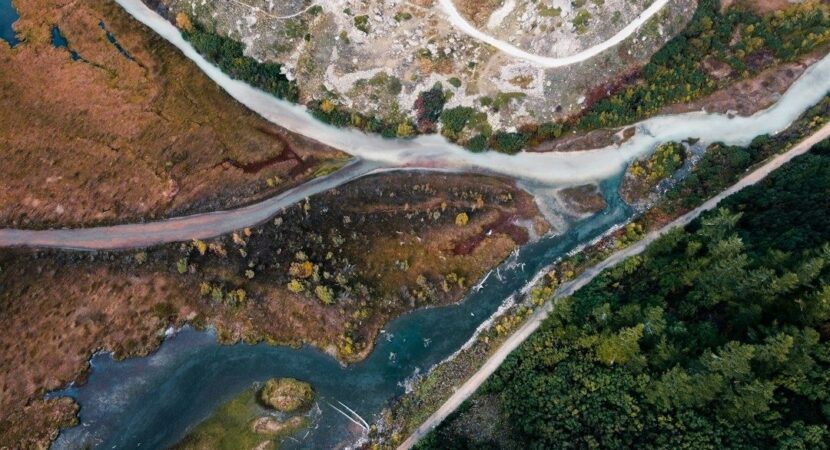Vue aérienne de deux cours d’eau se rejoignant parmi bois et graviers